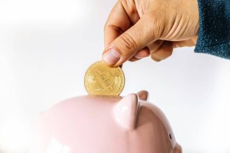 Main masculine plaçant une pièce de bitcoin dans une tirelire