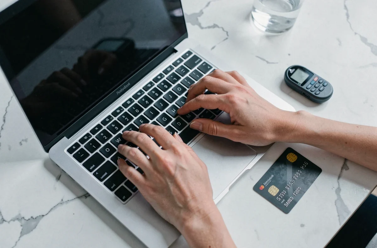 Vue en plongée de mains sécurisant un accès bancaire Société Générale avec un mot de passe sur ordinateur portable et un token de sécurité
